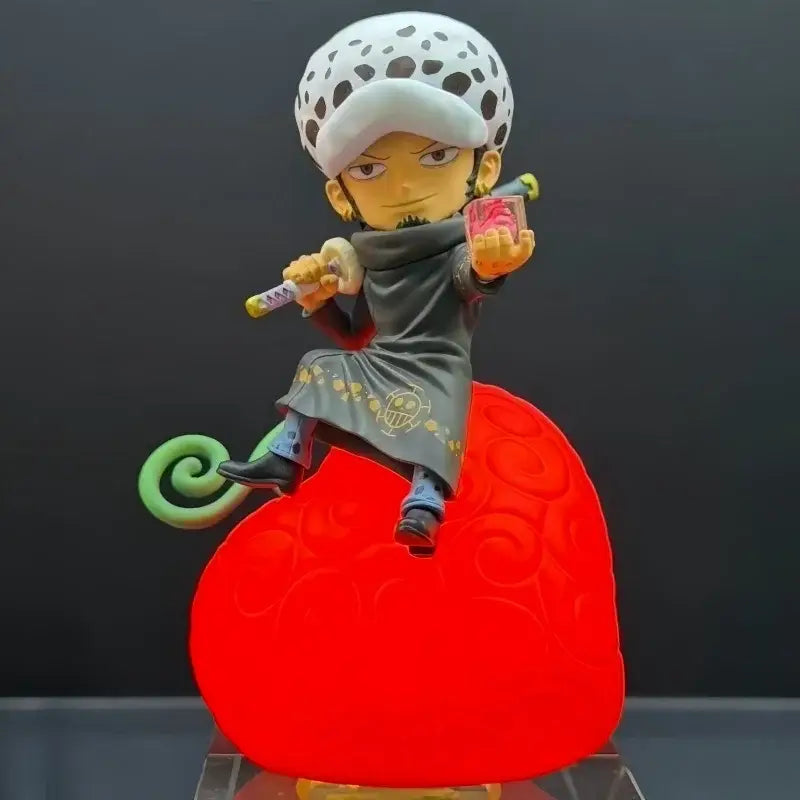 A detailed plastic figurine of a one piece devil fruit character with white hat, gold skull coat, on a red heart night light base