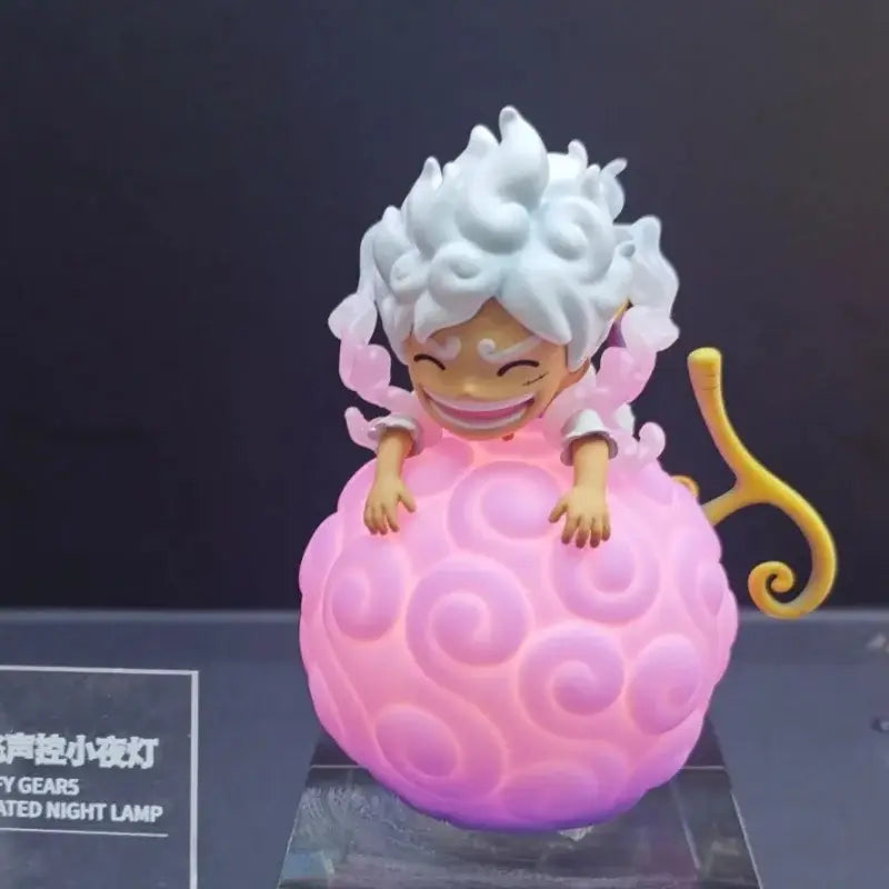 Pink glowing spherical one piece devil fruit night light with cheerful anime character and yellow curved handle
