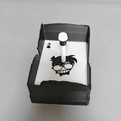 Black 3d-printed napkin holder with white interior featuring conan edogawa silhouette and ace of spades design for shadow light projector