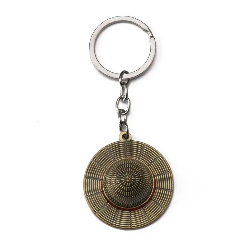 Bronze metal luffy hat keychain with detailed circular straw hat design and central starburst pattern pendant keyring