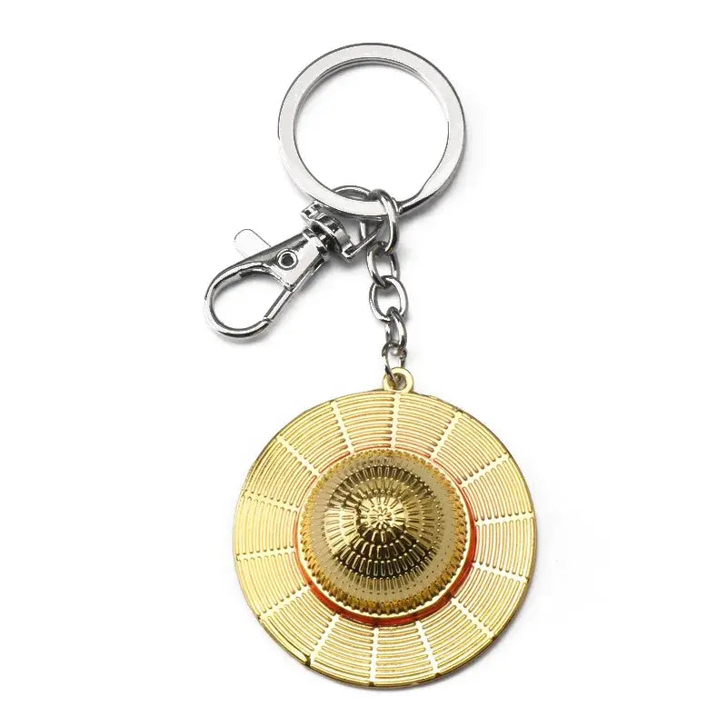 Gold-colored metal luffy hat keychain with detailed circular straw hat design and central emblem pendant keyring
