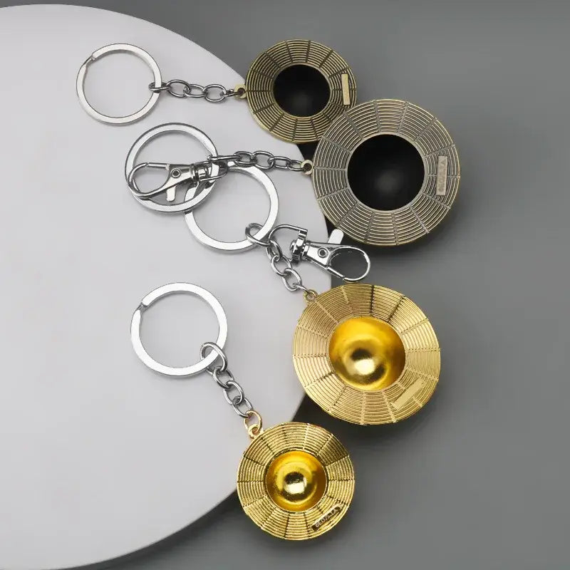 Gold and silver metallic one piece monkey d luffy hat keychain with circular disc design and central spherical element