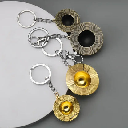 Gold and silver metallic one piece monkey d luffy hat keychain with circular disc design and central spherical element