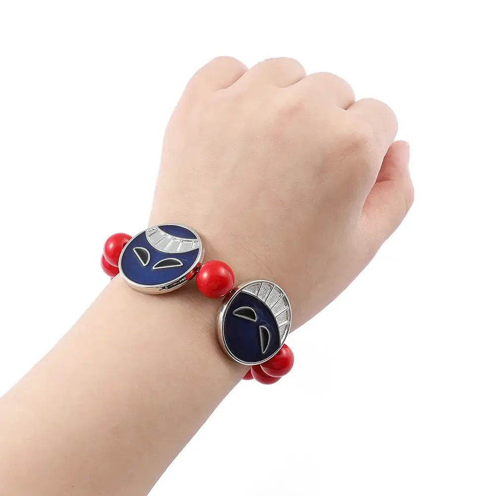 Red beads bracelet featuring two navy blue enamel charms with silver accents and stylized faces from one piece anime