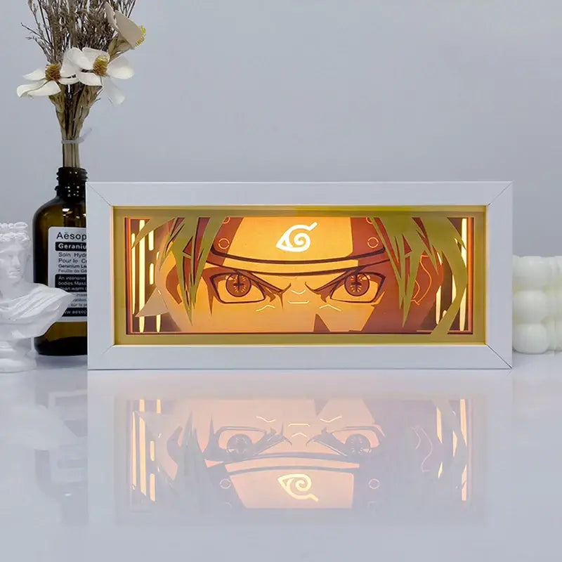 White-framed shadow box light featuring illuminated naruto face layered paper cutout with warm amber glow