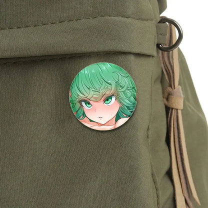 A round punch man saitama brooch pin with green hair and emerald eyes on an olive green fabric bag