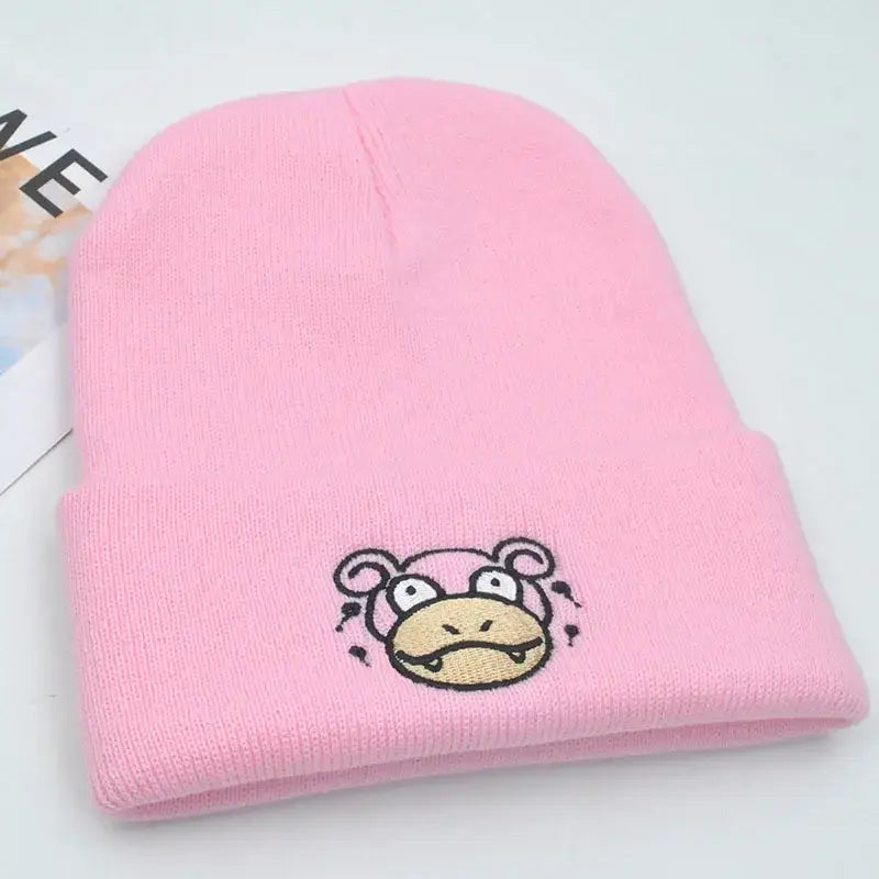 Pink knitted hood hat featuring an embroidered slowpoke cartoon face in plush knit style for pokemon fans