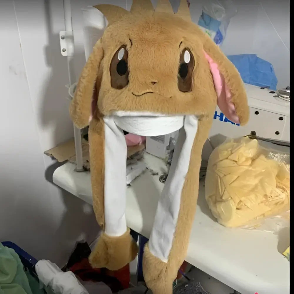 A plush tan eevee-themed airbag hat with pinch ears and white lining perfect for winter warm christmas gifts