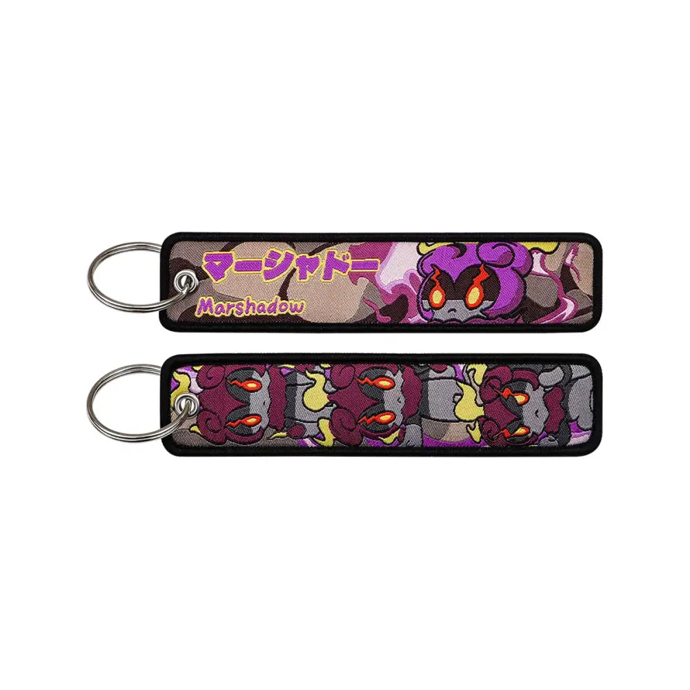 Pokemon pikachu embroidered keychain in purple and gray featuring marshshadow with fiery orange eyes and black border