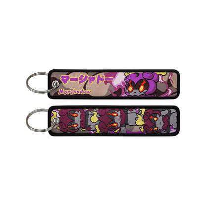 Pokemon pikachu embroidered keychain in purple and gray featuring marshshadow with fiery orange eyes and black border