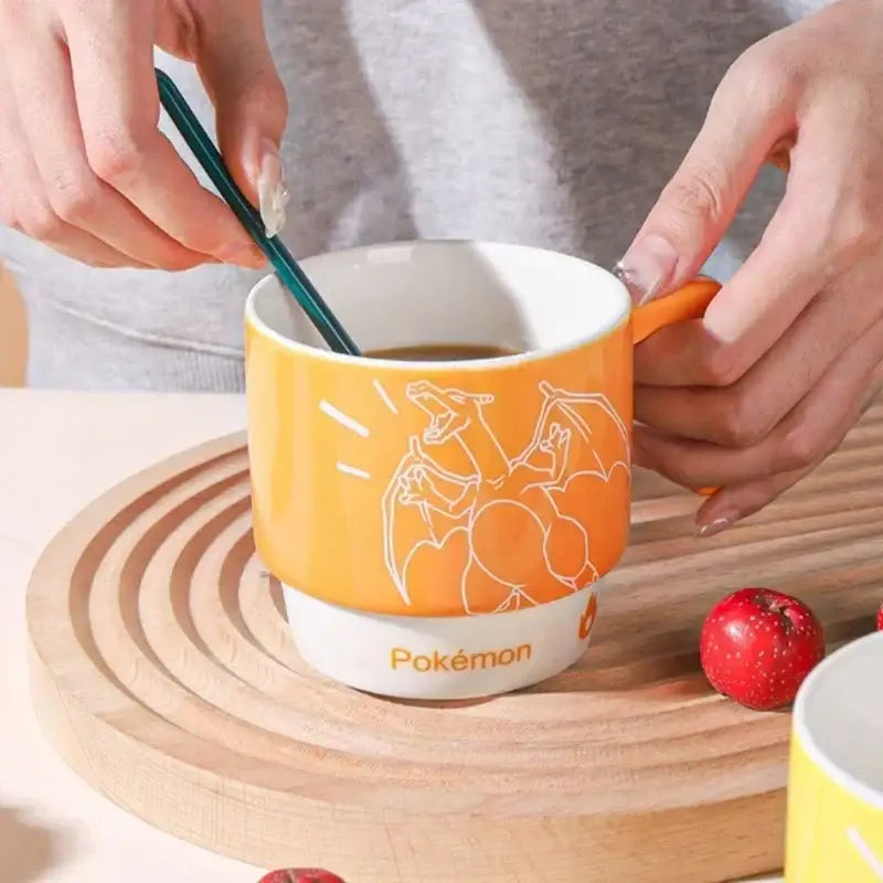 Orange ceramic mug featuring white charizard line art and pokémon branding in a stackable kawaii style design