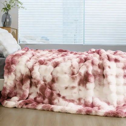 A plush faux rabbit throw blanket in soft pink and white tie-dye made of cozy thick faux fur for warmth
