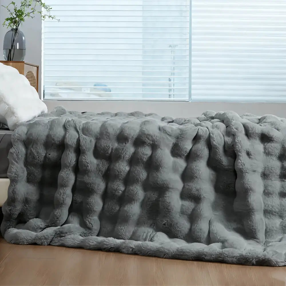 Gray plush faux rabbit fur throw blanket with thick soft textured surface and raised rounded tufts for cozy warmth