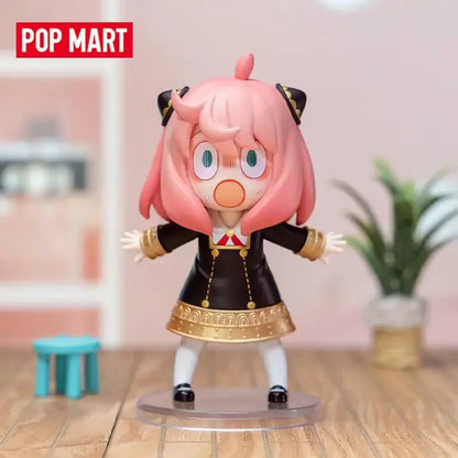 Pink-haired spy x family anya blind box figure in black and gold outfit standing on a clear desktop collectible base