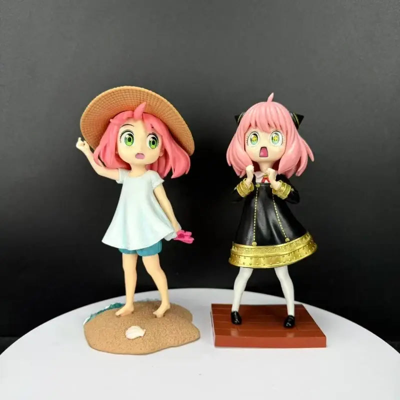 Two anime-style spy x family desktop pvc figurines featuring yor forger in black gold and pink hair straw hat outfits