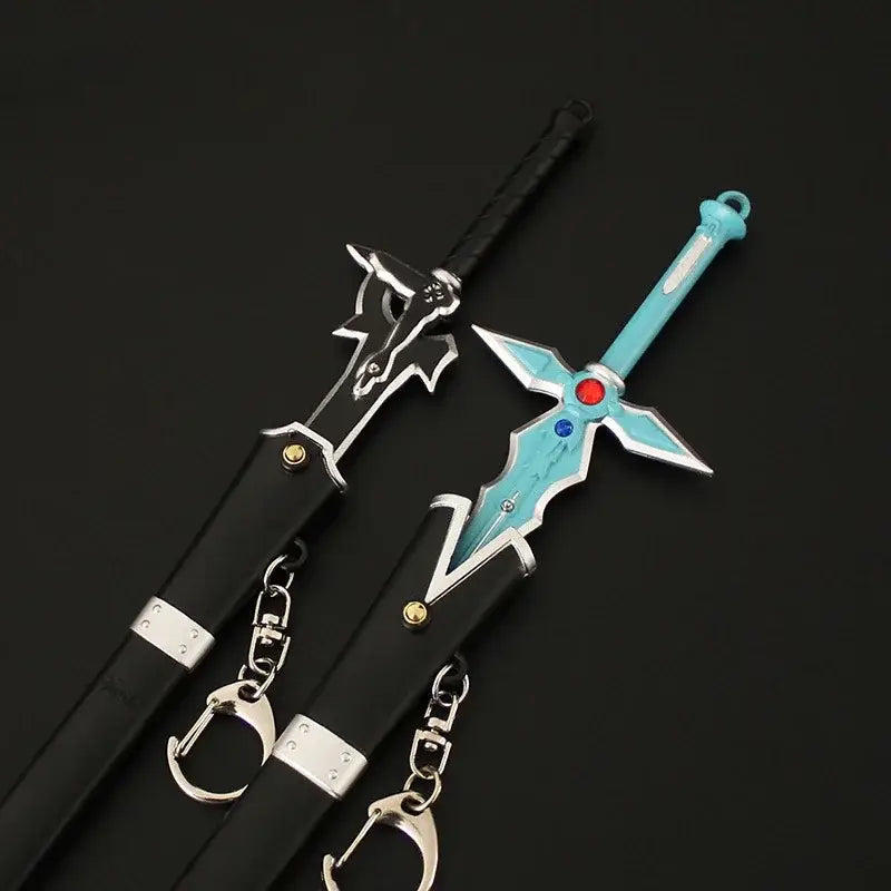 Two miniature sword art online keychains with black and turquoise metal blades featuring intricate gemstone designs