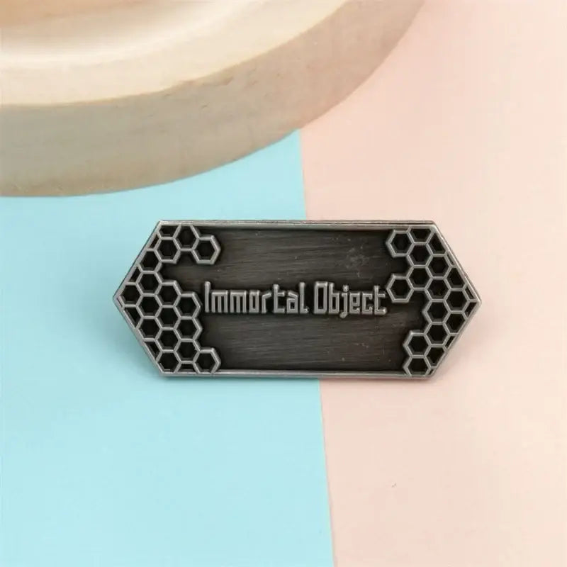 Dark metallic hexagonal sword art online enamel pin with honeycomb edges and immortal object silver lettering vintage badge