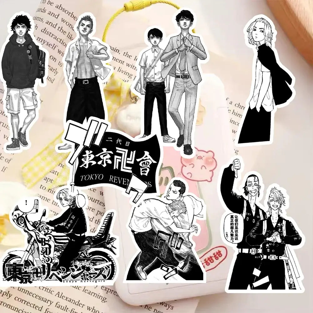 Black-and-white tokyo revengers anime character sticker decals arranged on a book page with a yellow keychain visible
