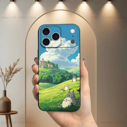 Vibrant blue soft silicone totoro phone case with detailed characters on back in a lush green landscape under bright sky