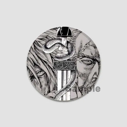 Circular black-and-white vinland saga anime badge pin featuring a sword with ornate hilt coiled by a snake and faces