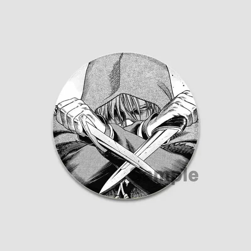 Black-and-white circular tinplate anime badge pin featuring a hooded manga character gripping crossed knives from vinland saga