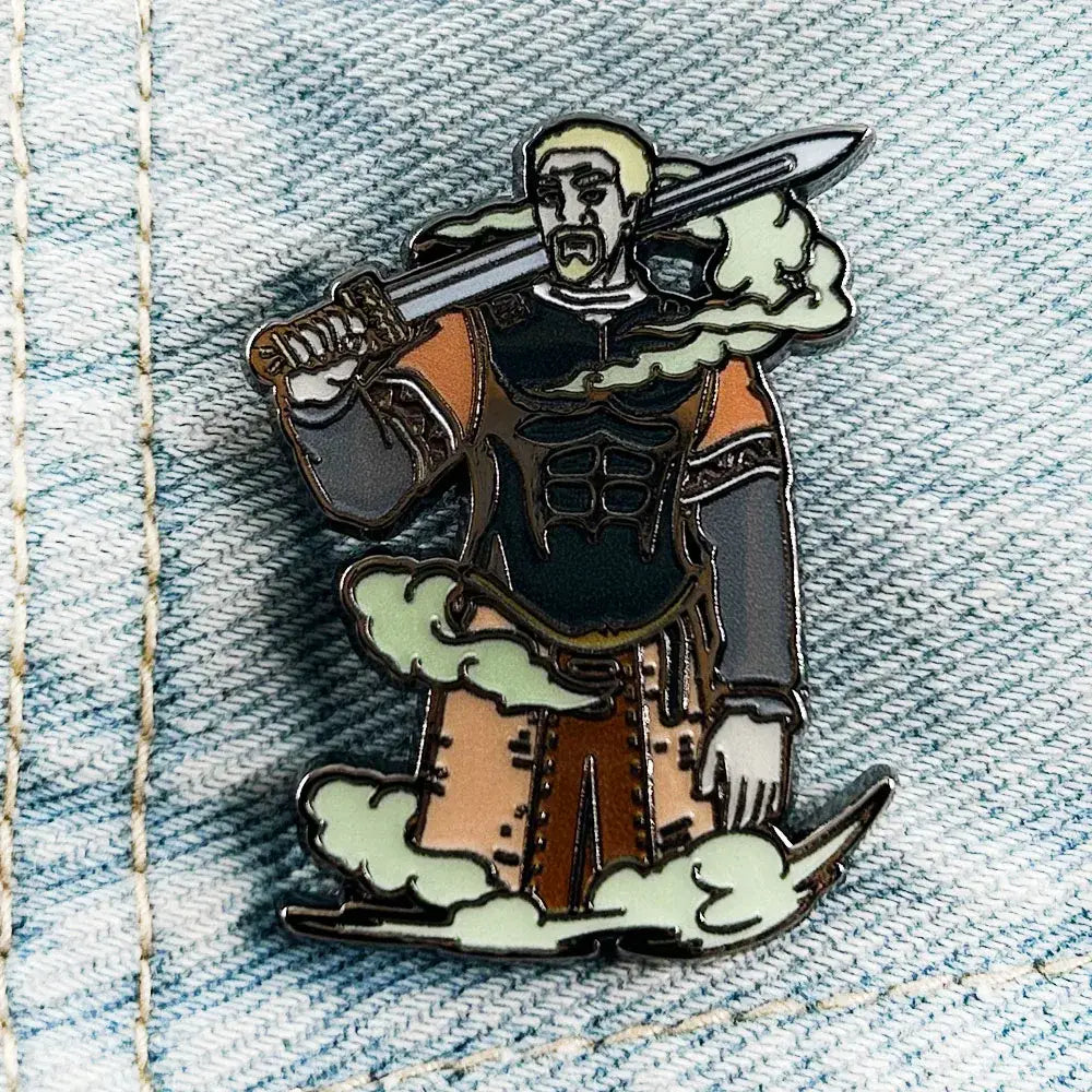 Detailed enamel askeladd lapel pin featuring a blonde warrior in black and orange armor with sword on green clouds