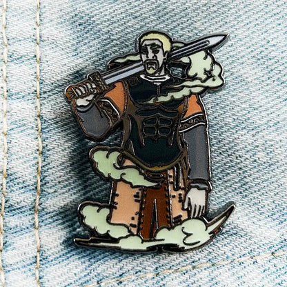 Detailed enamel askeladd lapel pin featuring a blonde warrior in black and orange armor with sword on green clouds