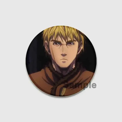 Circular vinyl saga badge pin featuring a blonde anime character in a brown coat made from handmade tinplate
