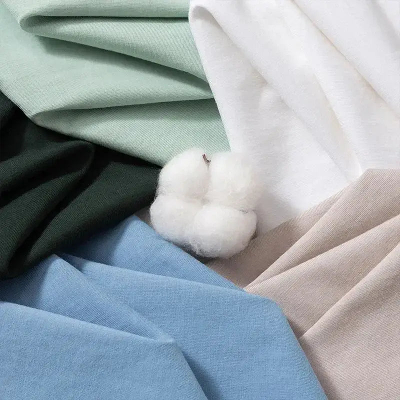 A fluffy white cotton boll rests on pastel fabrics next to a y2k vinland saga t-shirt featuring thorfinn and askeladd