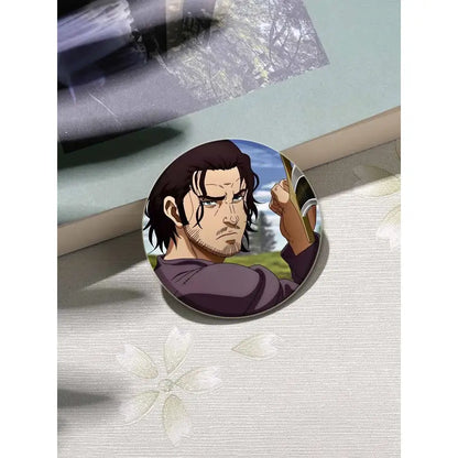 Circular vinland saga thorfinn button brooch featuring a determined man with dark hair in a purple shirt outdoors