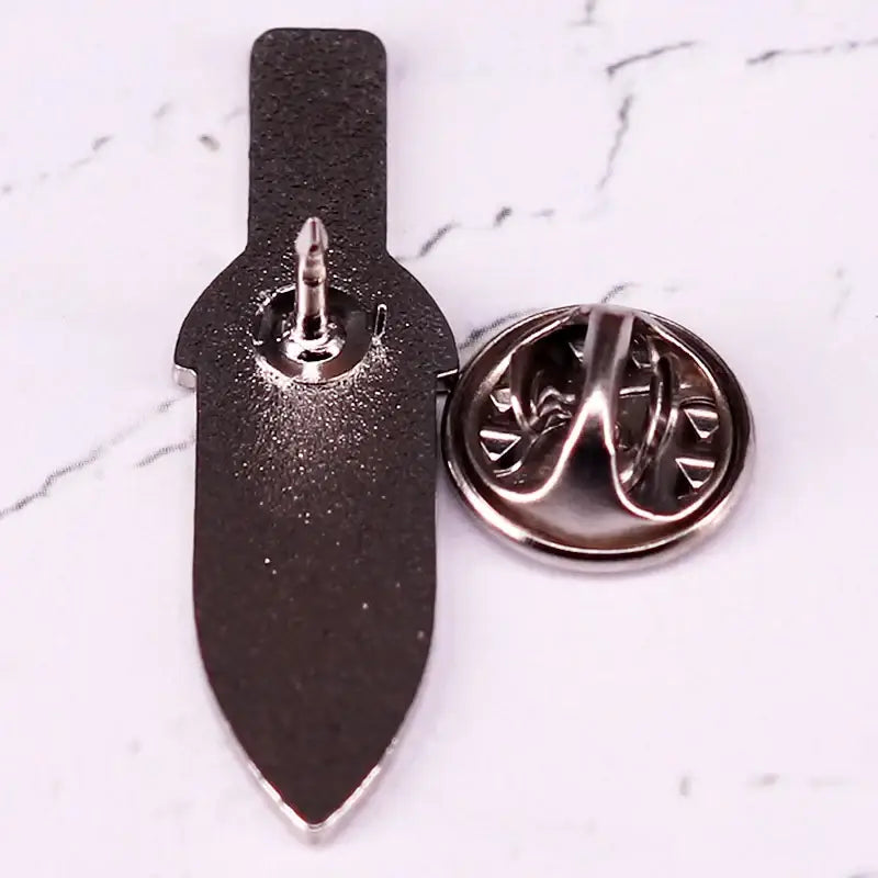Black hard enamel vinland saga thorfinn dagger enamel pin with silver toned metal clasp and backing shown from back side