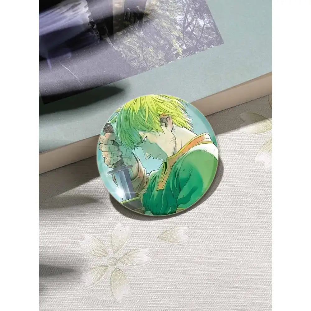 Circular vinland saga thorfinn enamel pin with vibrant green hair and sword on light blue background 58 by 32mm