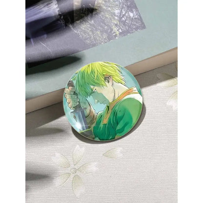 Circular vinland saga thorfinn enamel pin with vibrant green hair and sword on light blue background 58 by 32mm