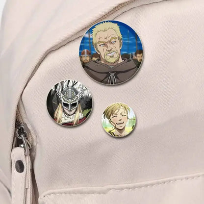 Three vibrant circular vinland saga thorfinn enamel pins handmade on light fabric featuring distinct colorful designs