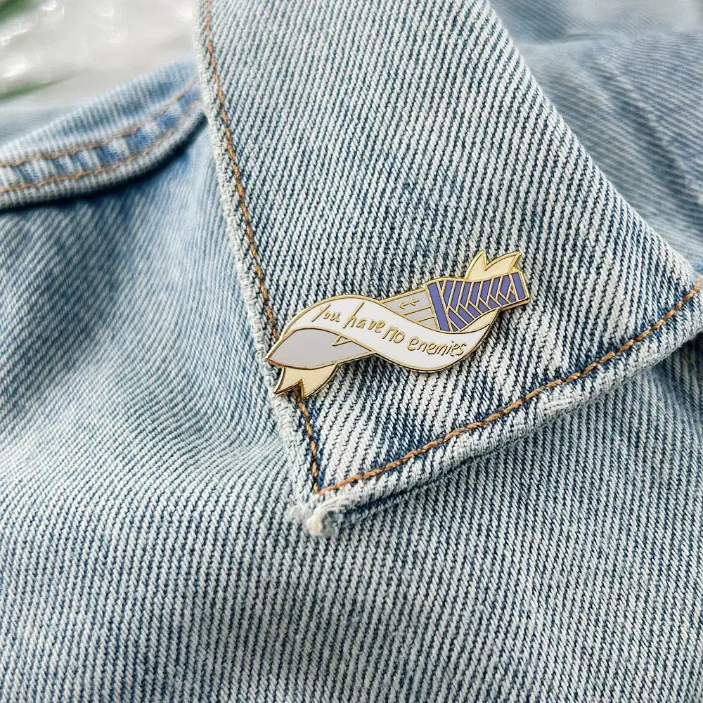 Metallic vinland saga thorfinn enamel pin with ribbon design and you have no enemies in gold purple and white colors