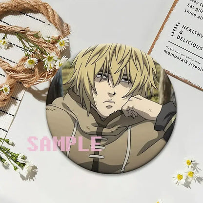 Circular vinland saga thorfinn lapel pin featuring an anime character with blonde hair in beige hooded outfit